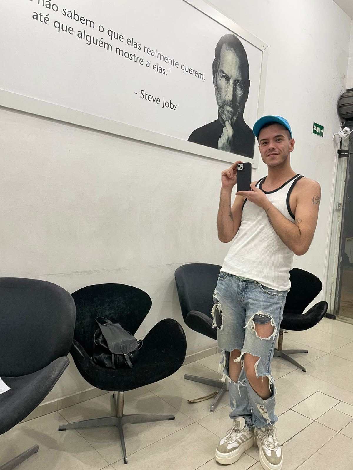 Cliente de regata e boné fotografando o celular na sala de espera da iPlanet