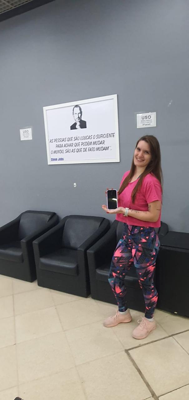 Cliente de camiseta rosa com o iPhone na sala de espera da iPlanet em São Caetano do Sul