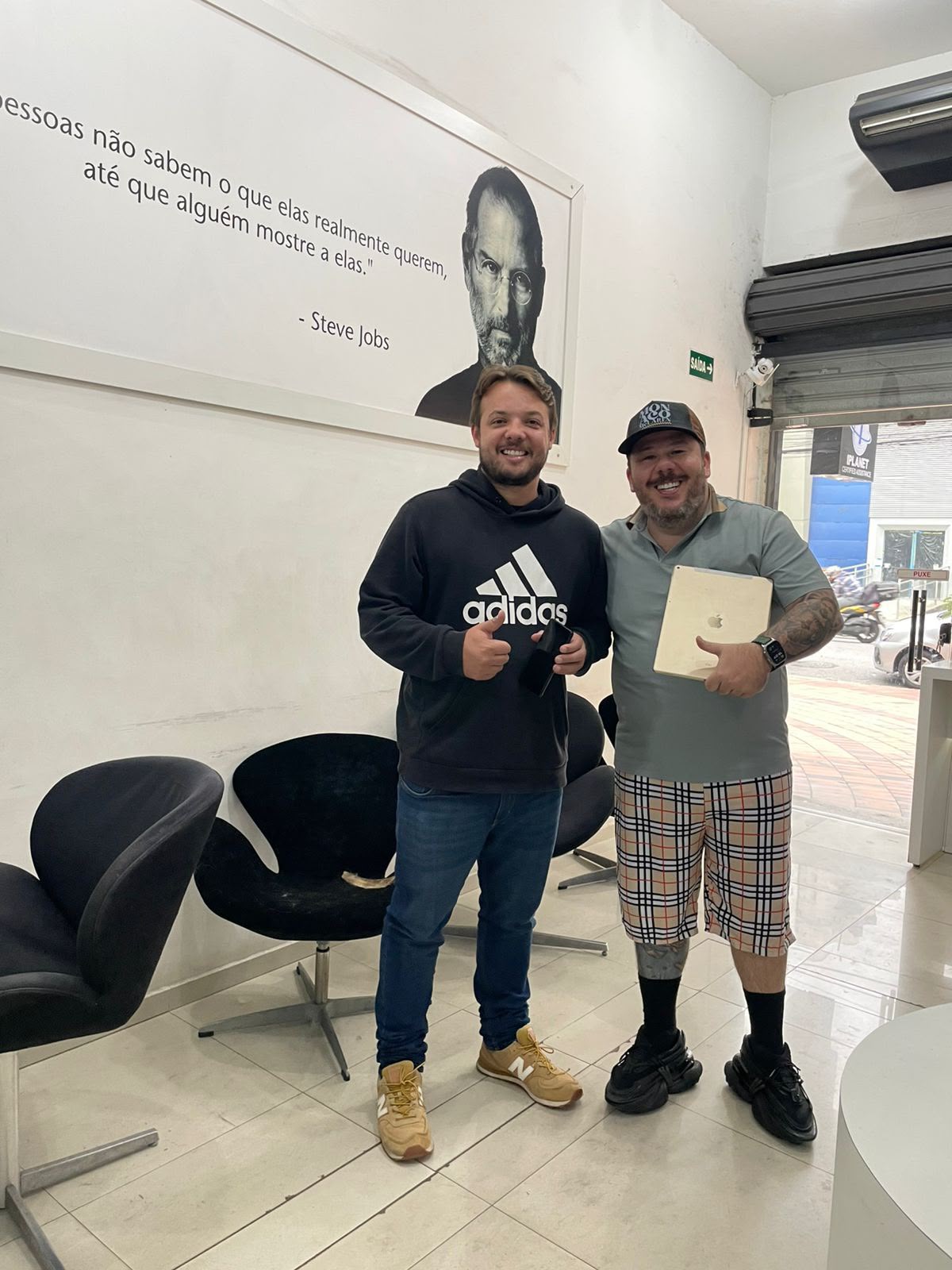 Dois clientes sorrindo na loja iPlanet, um deles com o iPad
